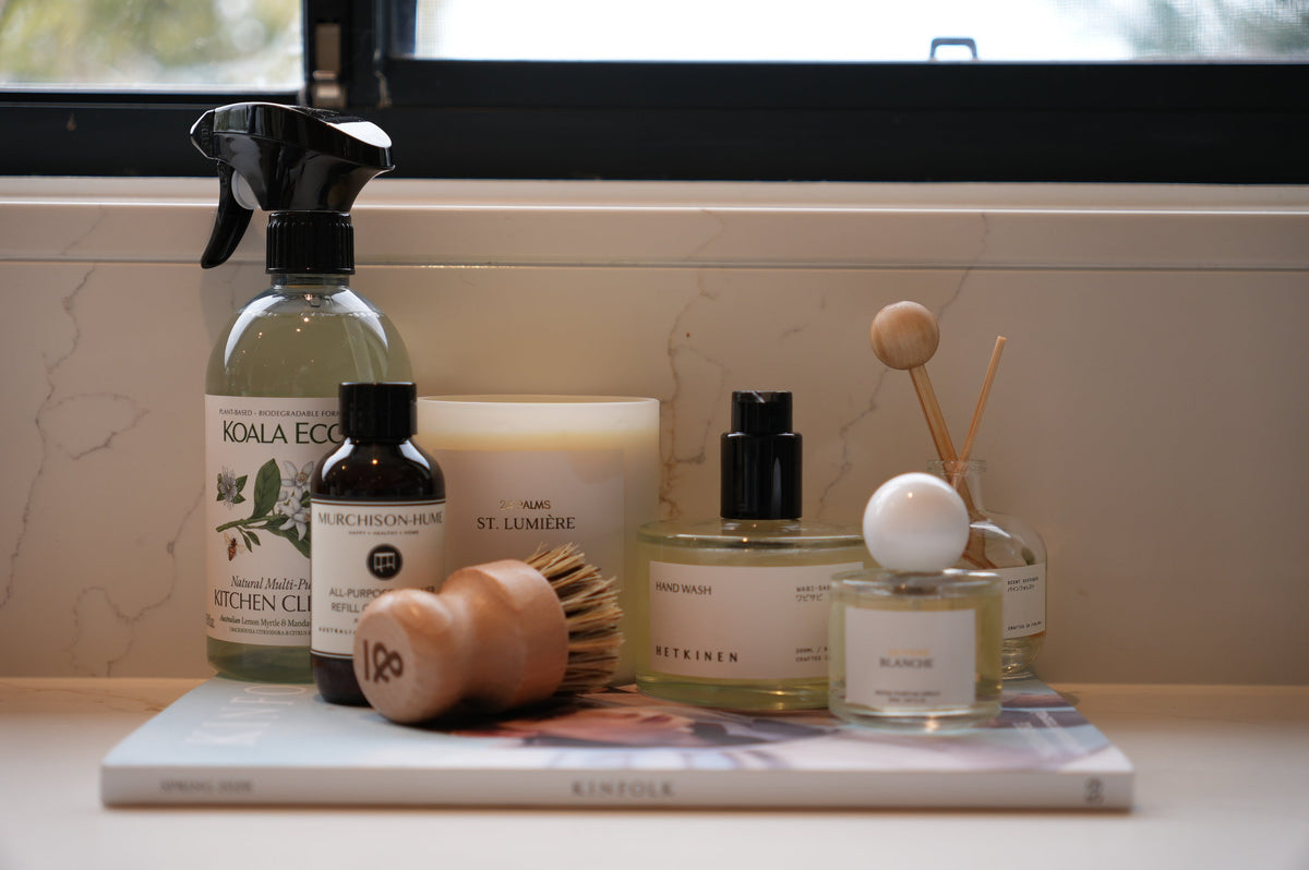 Low-tox cleaning products on a kitchen bench, including Murchison-Hume and refillable glass bottles