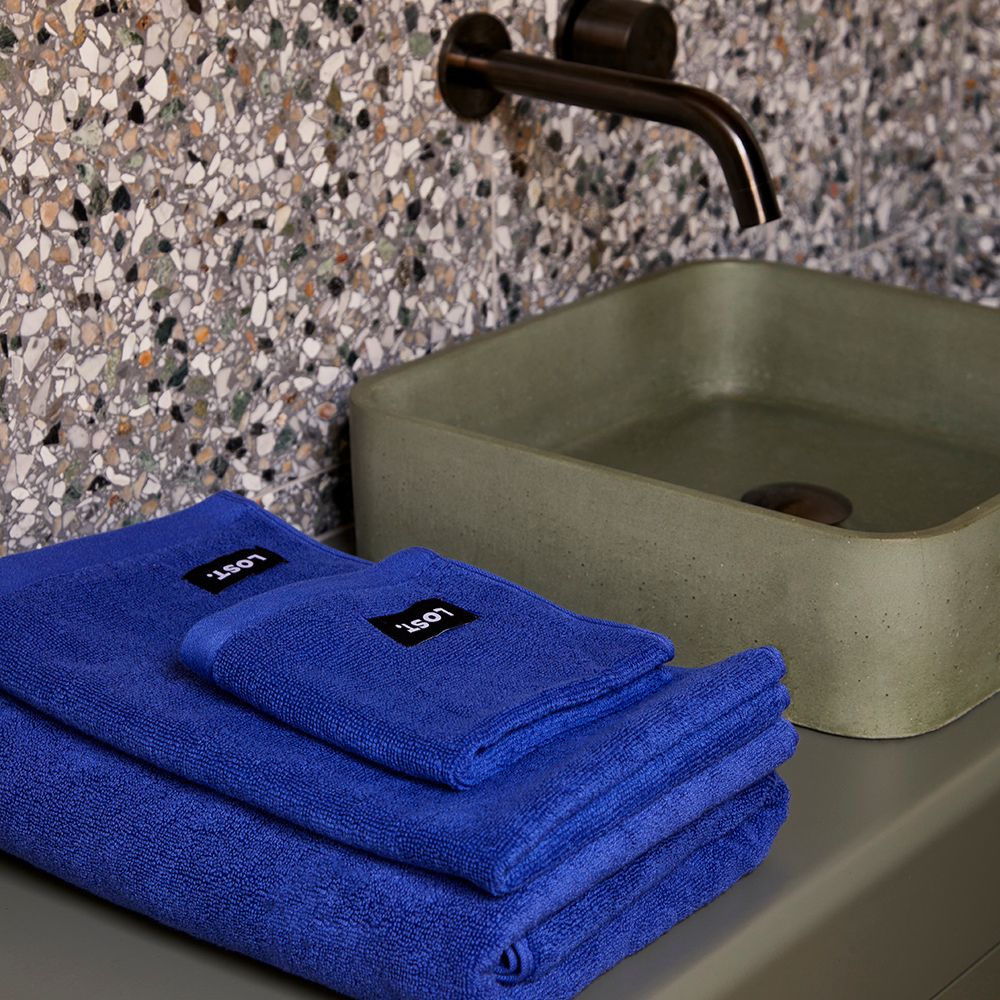 Lost Towels Electric Blue folded towels on a concrete vanity