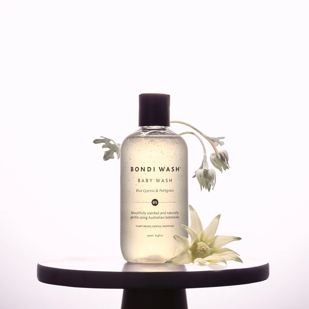 Bondi Wash Baby Wash bottle styled on a plinth with native flannel flowers