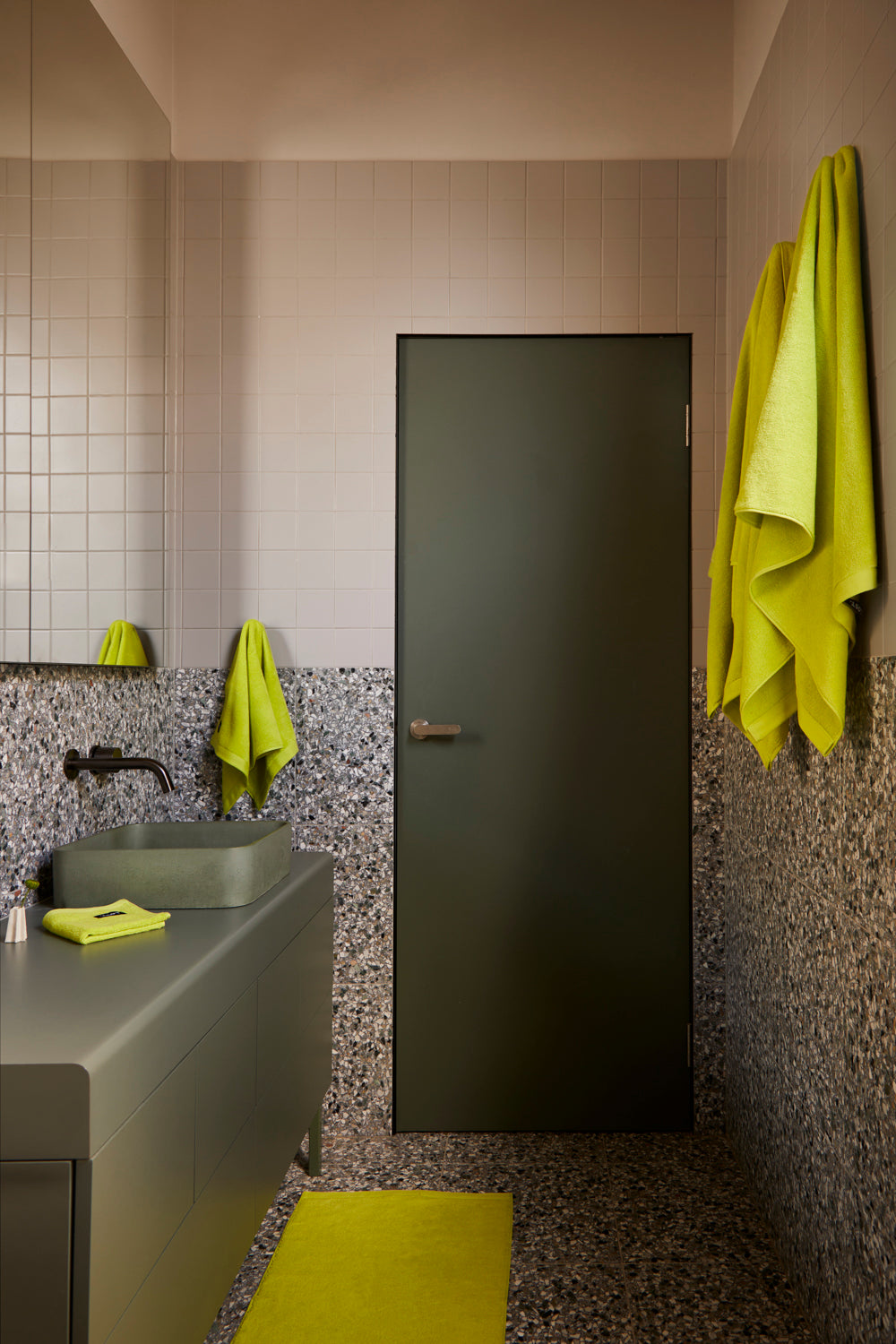 Lost Towels Chartreuse towels styled in a tiled bathroom