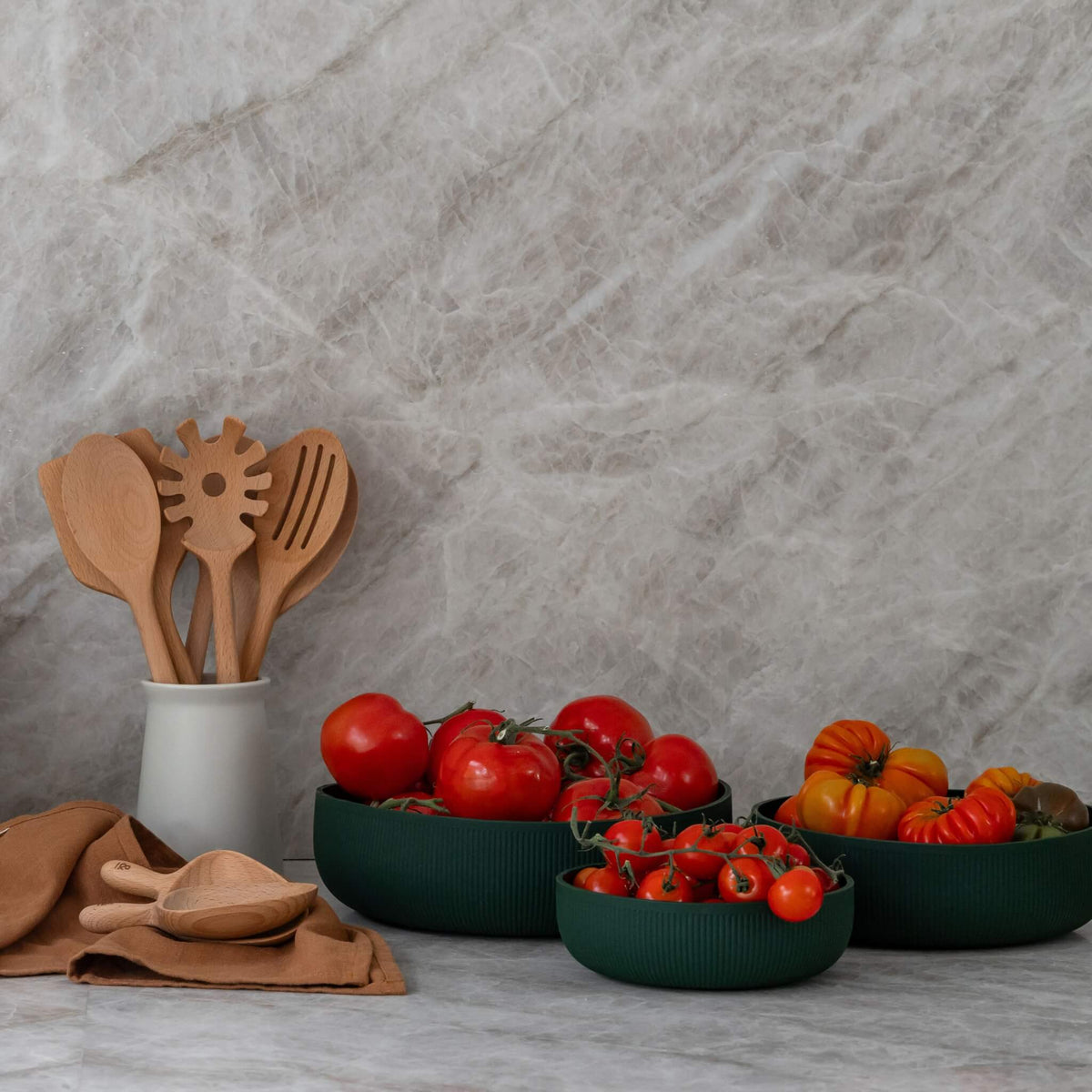 Beechwood utensils in a crock beside bowls of heirloom tomatoes