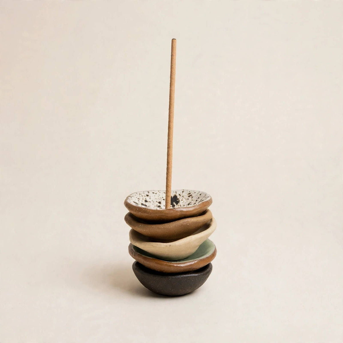 Stacked handmade ceramic incense holder bowls with an incense stick through the centre