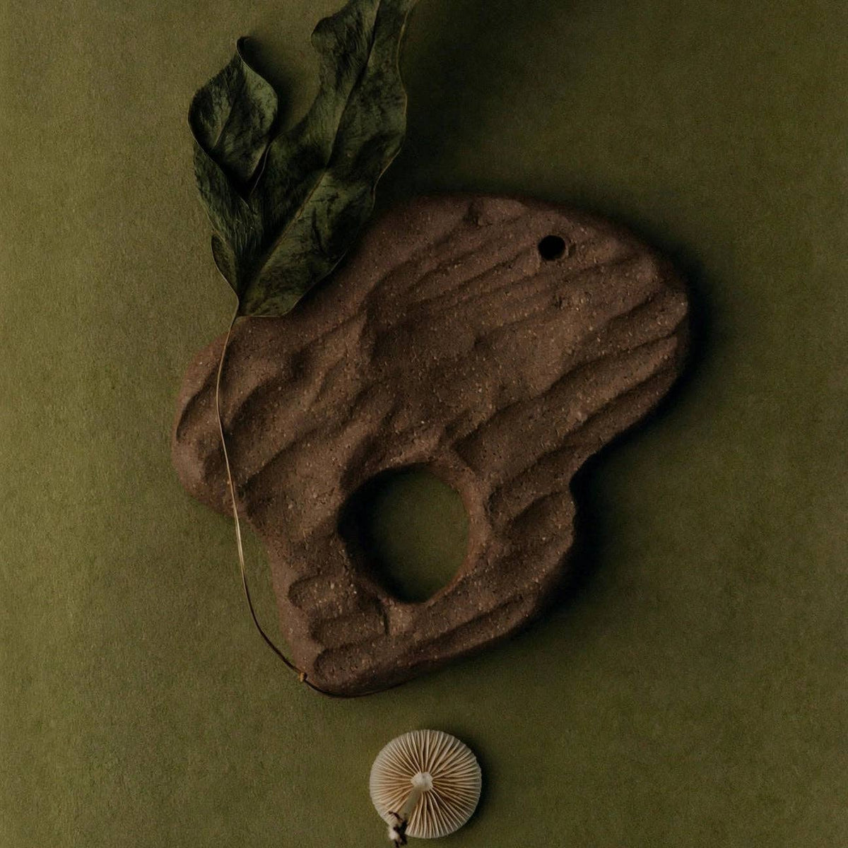 Handmade tree bark shaped ceramic incense holder styled with a dried leaf