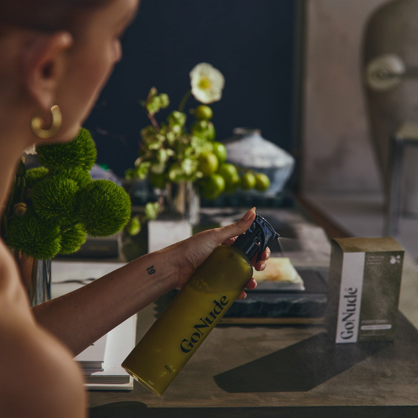 Go Nude Everything surface cleaner being sprayed from an olive refillable bottle beside its carton
