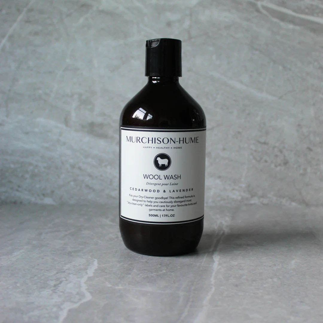 A dark amber bottle of Murchison-Hume Wool Wash with a white label, set against a gray marble-textured background.