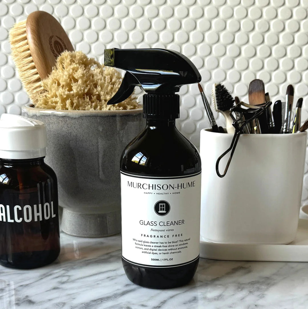 Murchison-Hume glass cleaner bottle on a marble surface with cleaning supplies in the background.