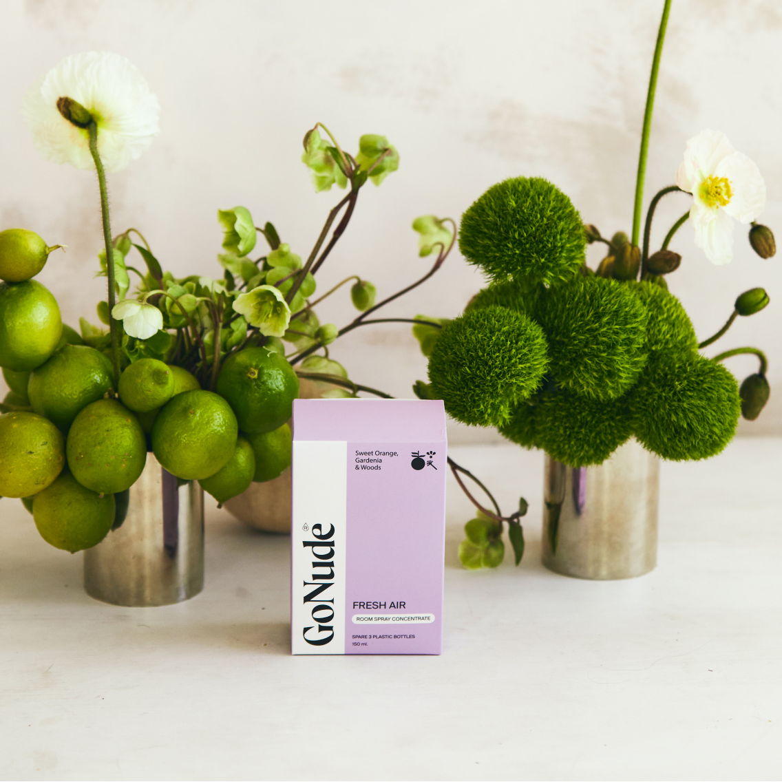 Go Nude Fresh Air room spray concentrate carton styled with limes, poppies and green foliage
