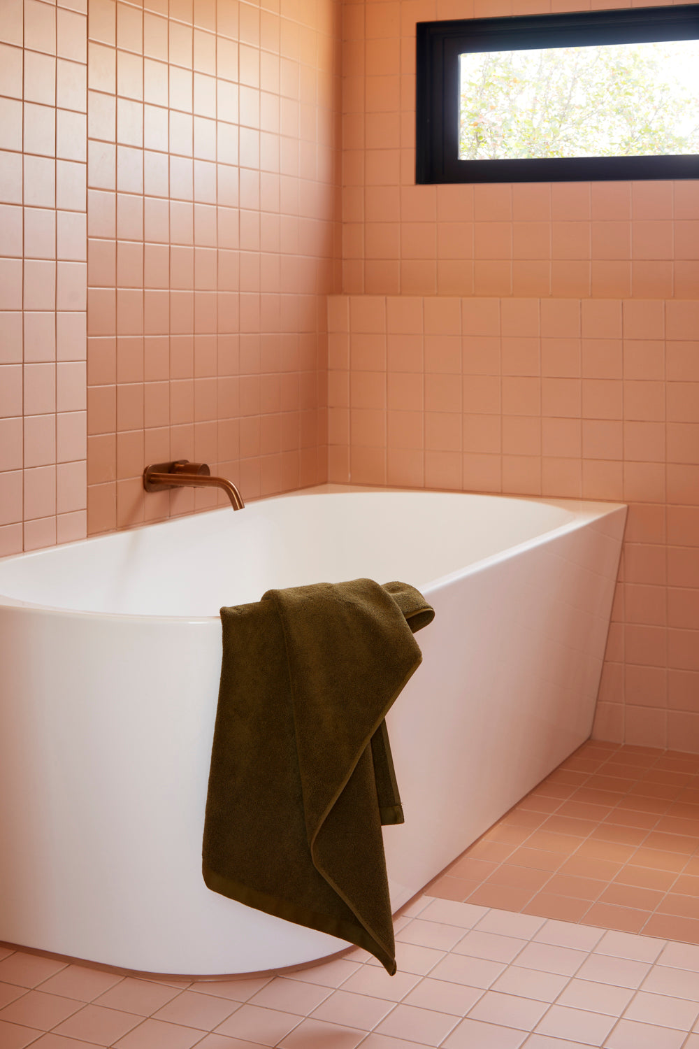 Lost Towels Khaki bath towel styled over a bath in a tiled bathroom