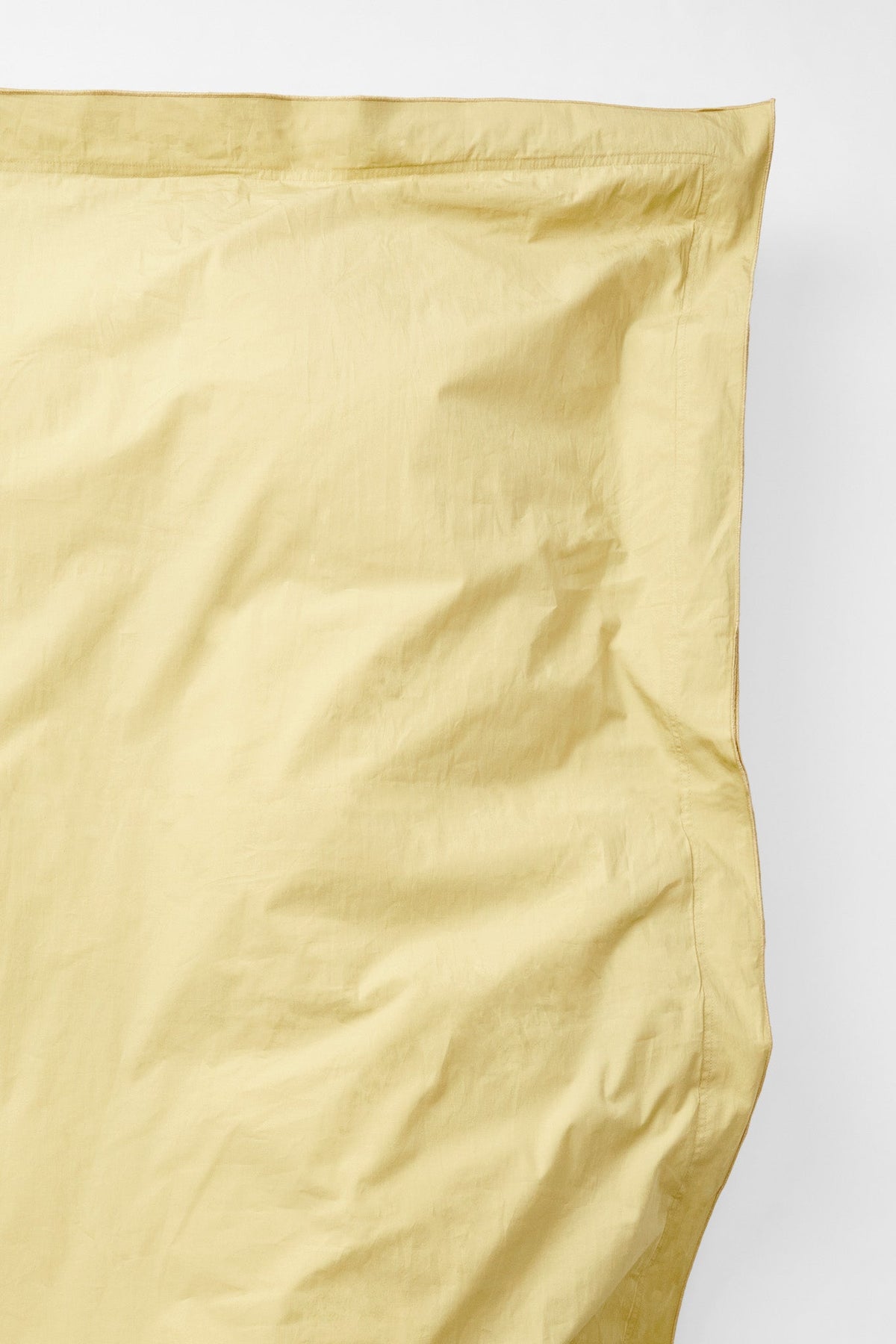 Overhead corner detail of the Studio Sutram Maize duvet cover in soft yellow percale
