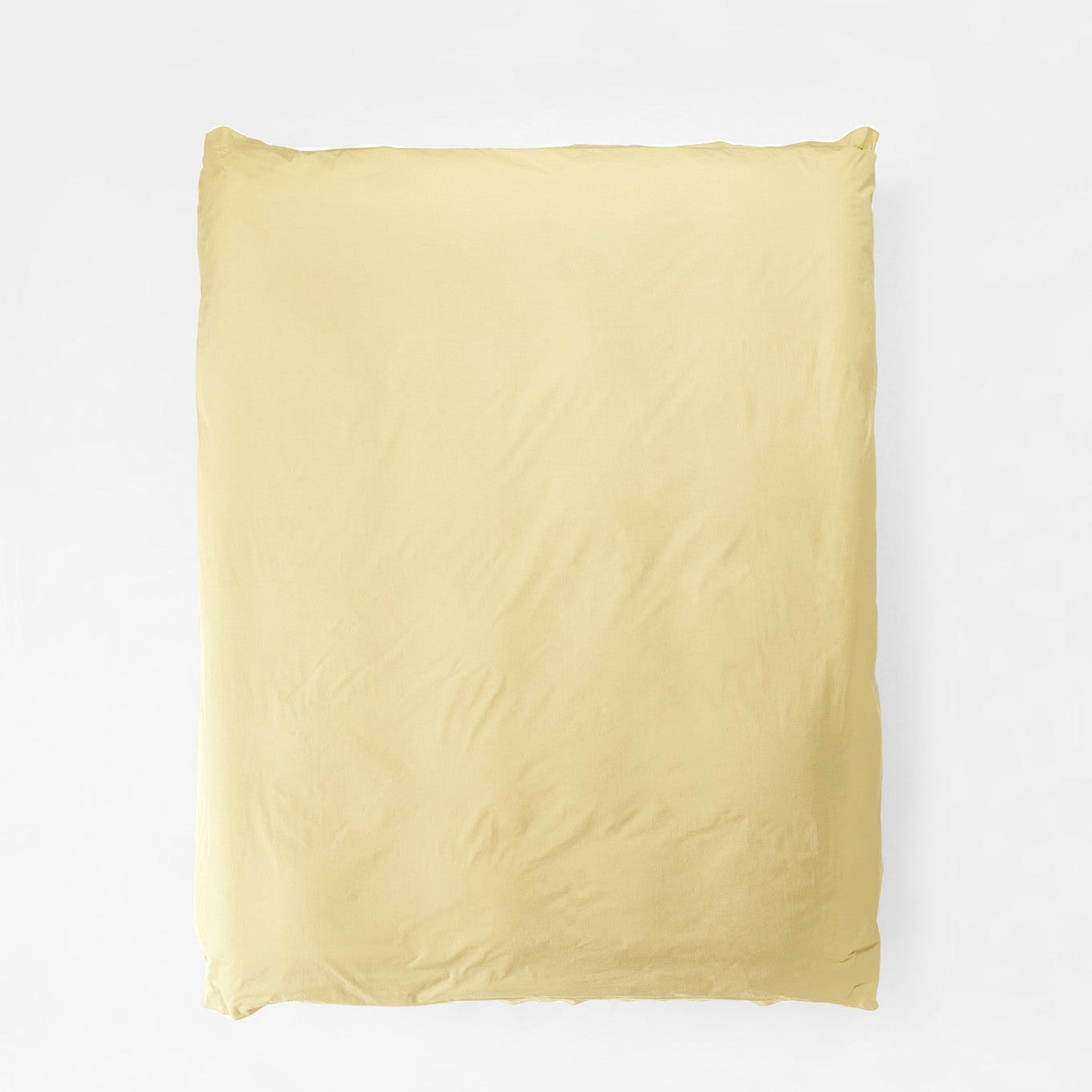 Studio Sutram Maize duvet cover in soft yellow organic cotton percale on a bed
