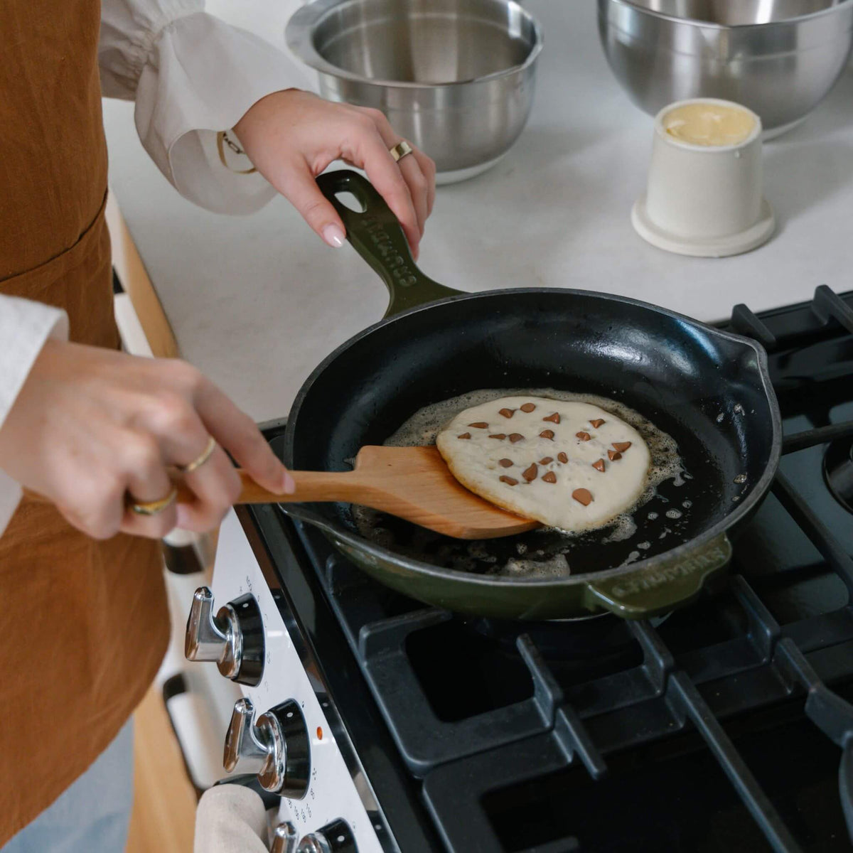 The beechwood turner lifting a pancake in a non-stick pan