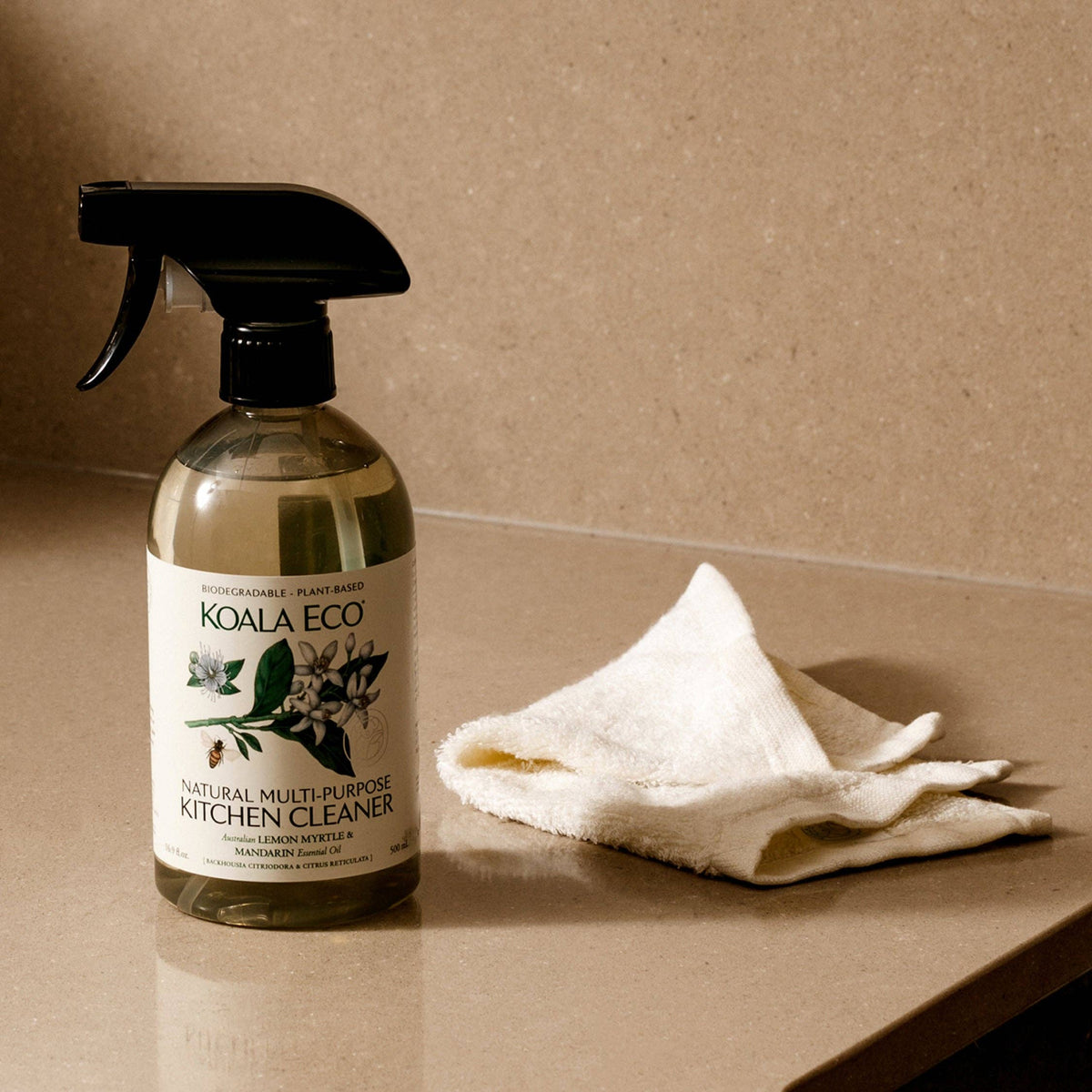 Koala Eco bamboo cleaning cloth folded on a stone benchtop beside a Koala Eco natural kitchen cleaner spray