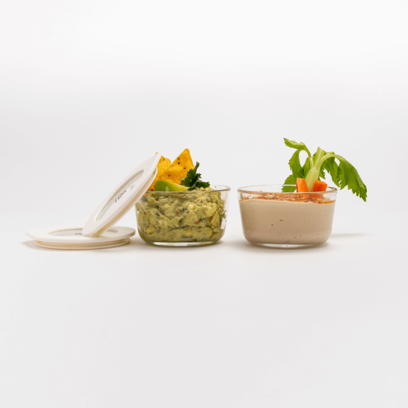 Guacamole and a creamy dip in two Oat Milk glass bowls with a lid set to one side