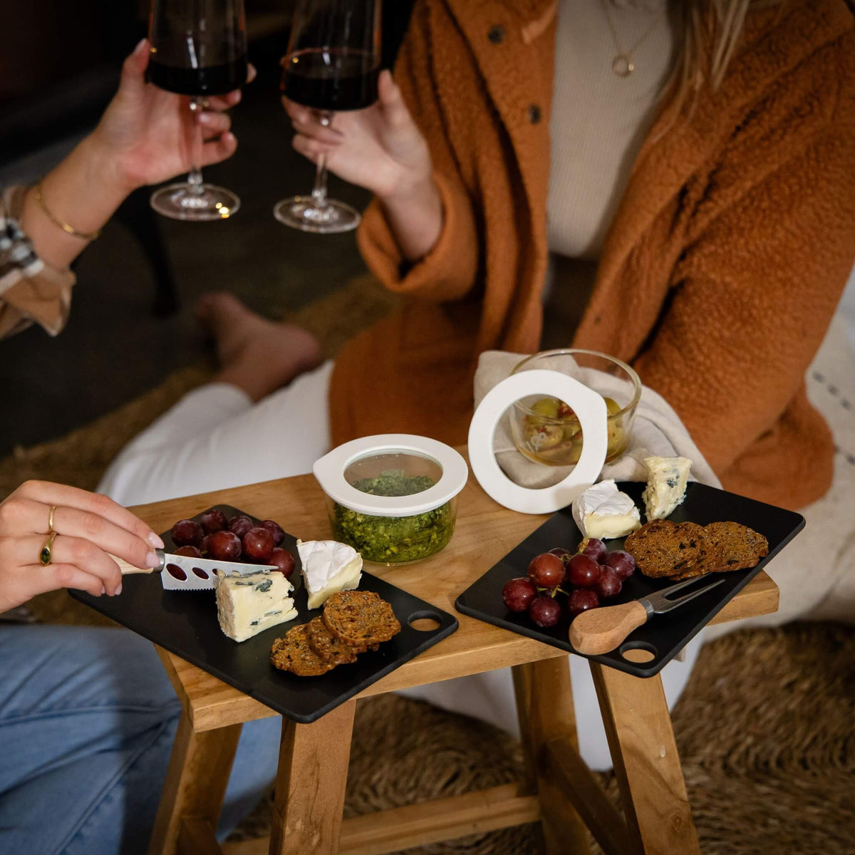 Glass dip bowls on a grazing table with cheese, crackers and wine