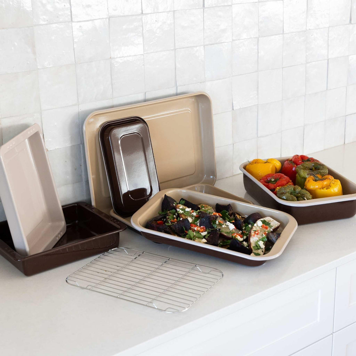 Macadamia enamel roasting dishes on a kitchen bench with roasted vegetables, styled with other pieces from the enamel range