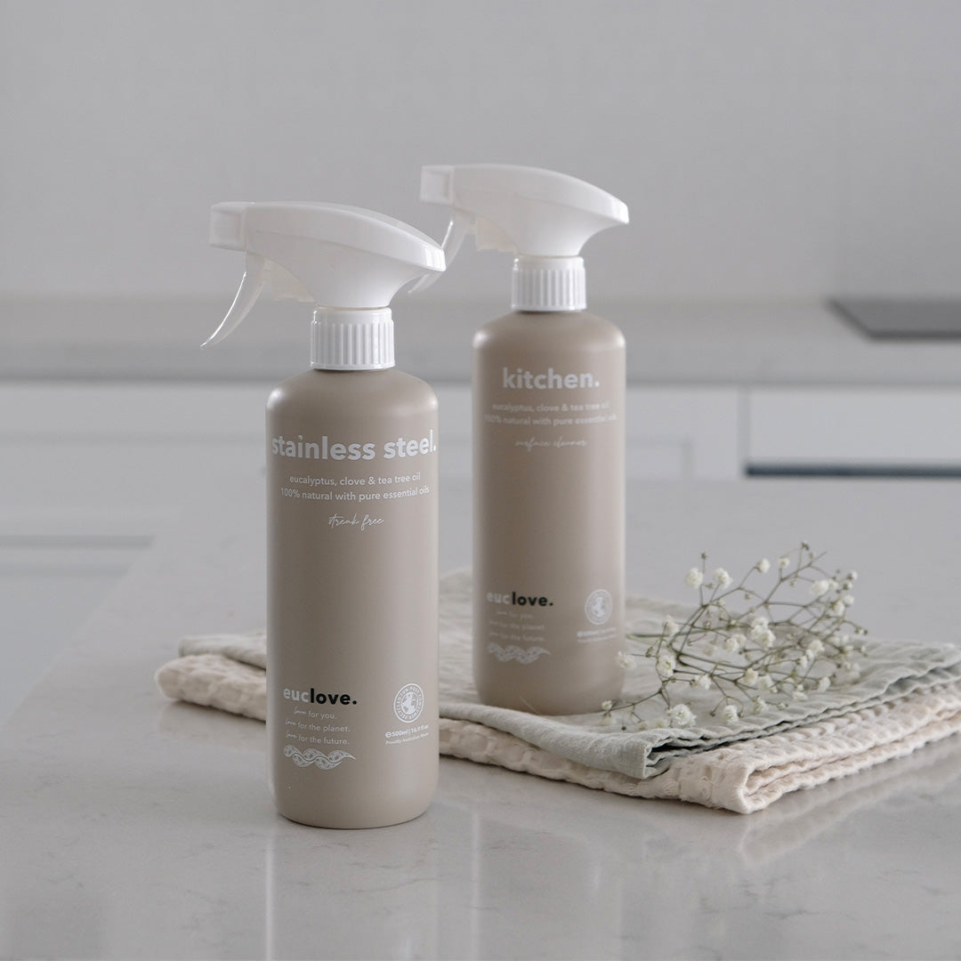 Euclove stainless steel cleaner spray on a marble benchtop with linen cloths and a sprig of baby's breath