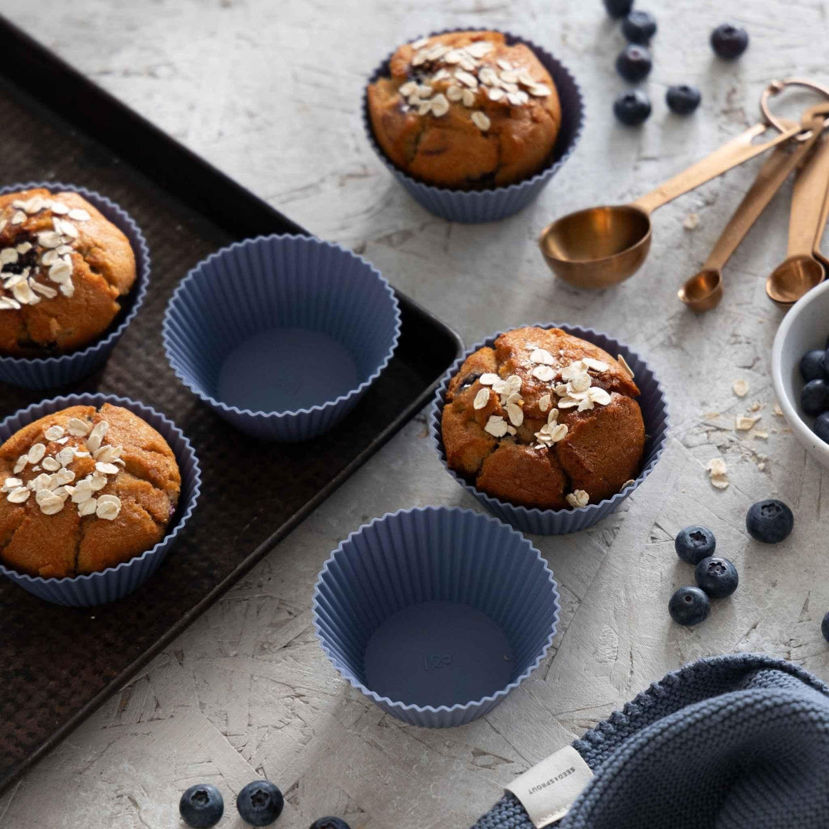 Blueberry silicone muffin cups on a baking tray with freshly baked muffins