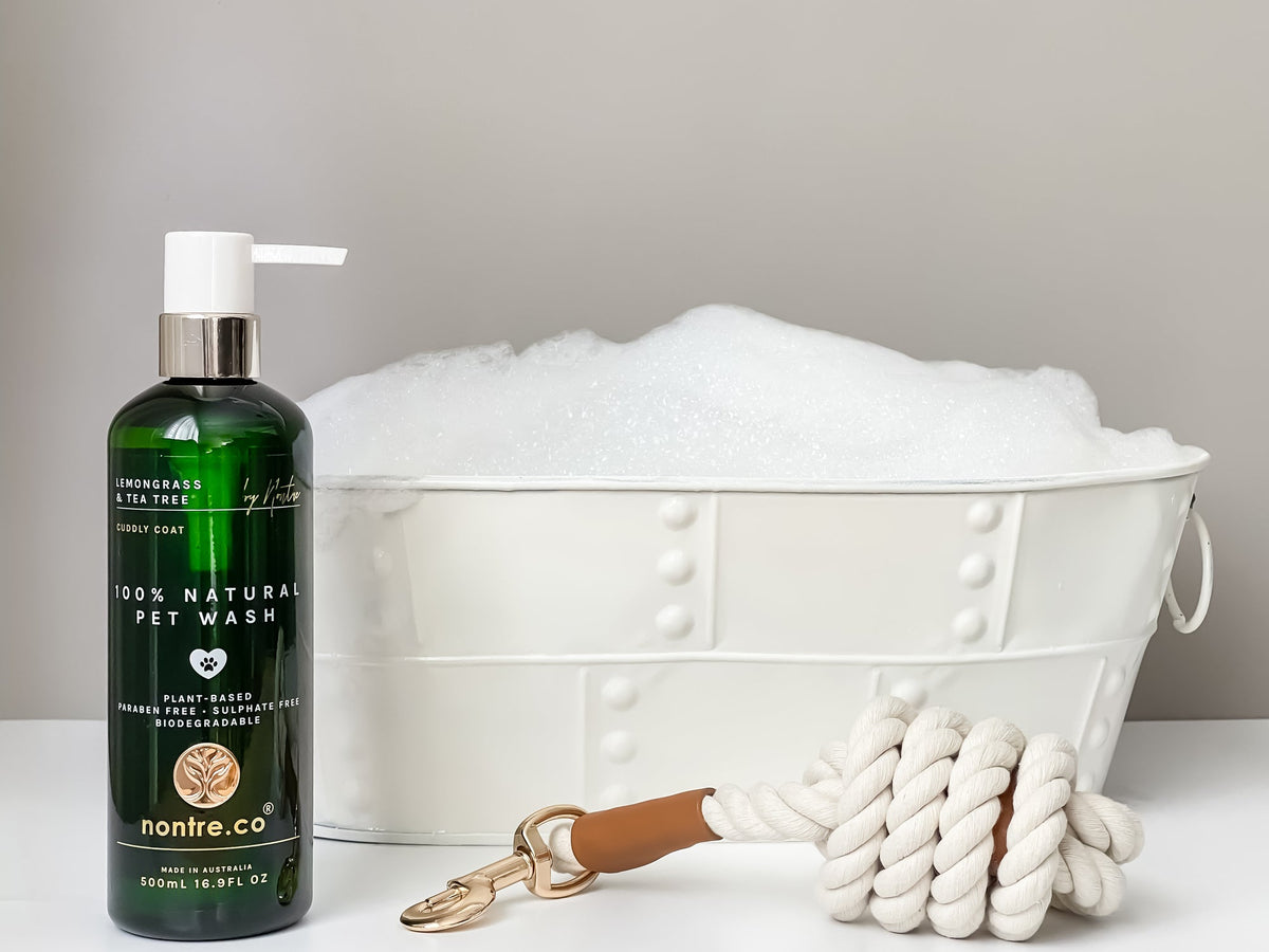 Nontre.co Cuddly Coat pet wash beside a bath tub of suds and a rope dog lead