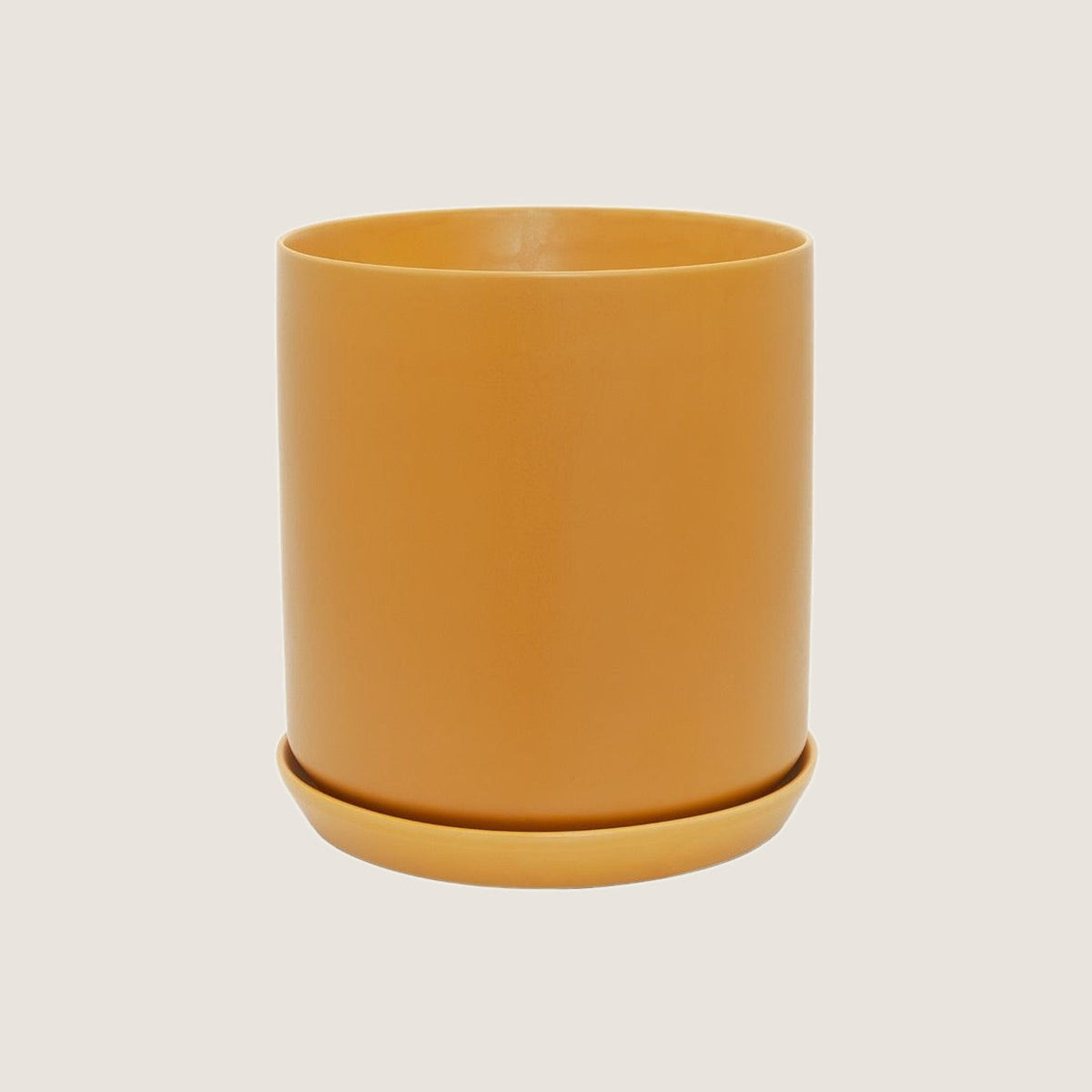 Potted XL Oslo planter in Tobacco with saucer, on a greige background