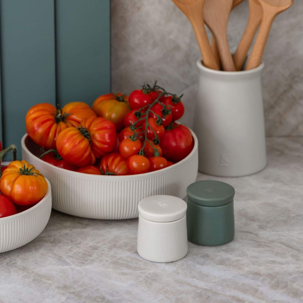 Ceramic salt and pepper pods on a kitchen bench beside a bowl of tomatoes
