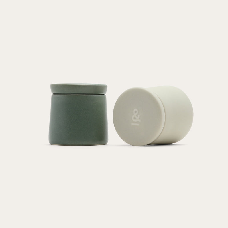 The pair of ceramic salt and pepper pods, one sage and one cream, with lids