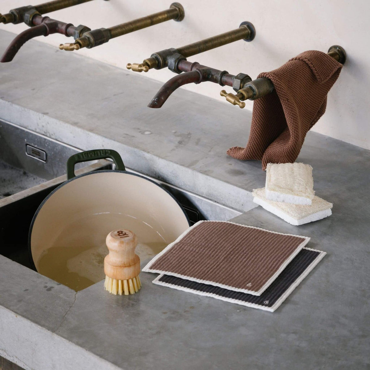 Compostable sponge on a kitchen bench beside a dish brush and board