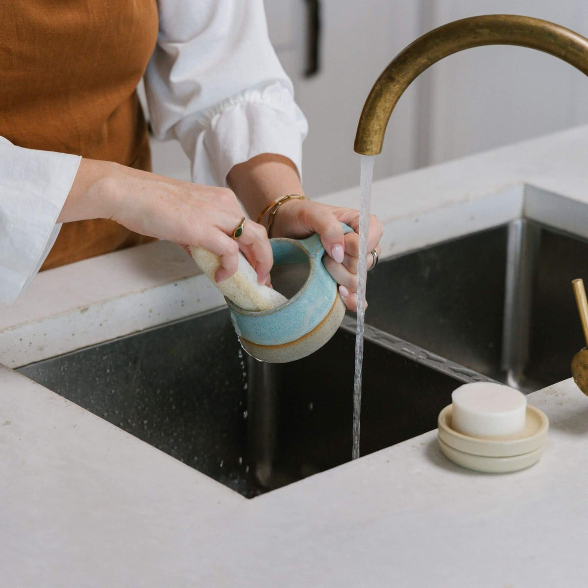 Rinsing the compostable sponge under a kitchen tap